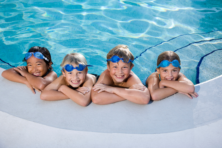 Children smiling at edge of swimming pool